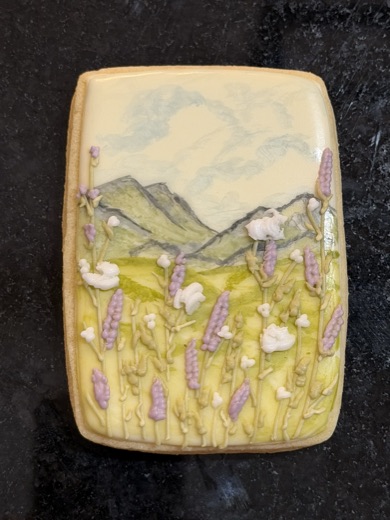 Hand-painted lavender field and mountains on a decorated sugar cookie